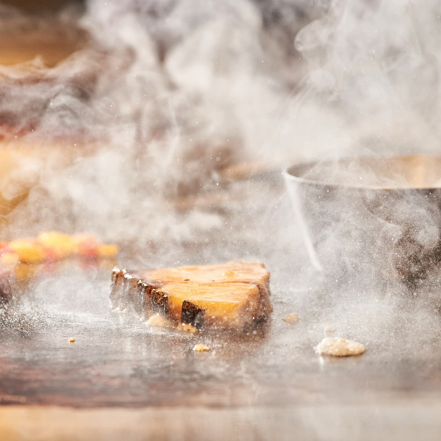 鉄板の上で豪快に焼かれる肉料理と立ち上る熱い湯気、弾ける脂の躍動感あふれるシズルカット no.2