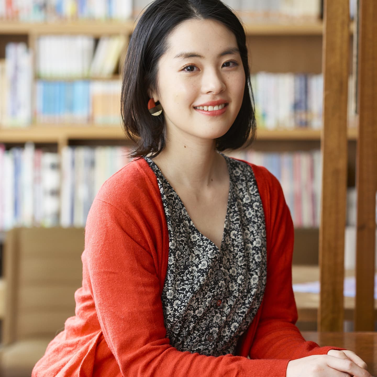 本棚を背景にした知的な女性のプロフィール写真。被写体の自然な美しさとブランドの空気感を共鳴させるライティング