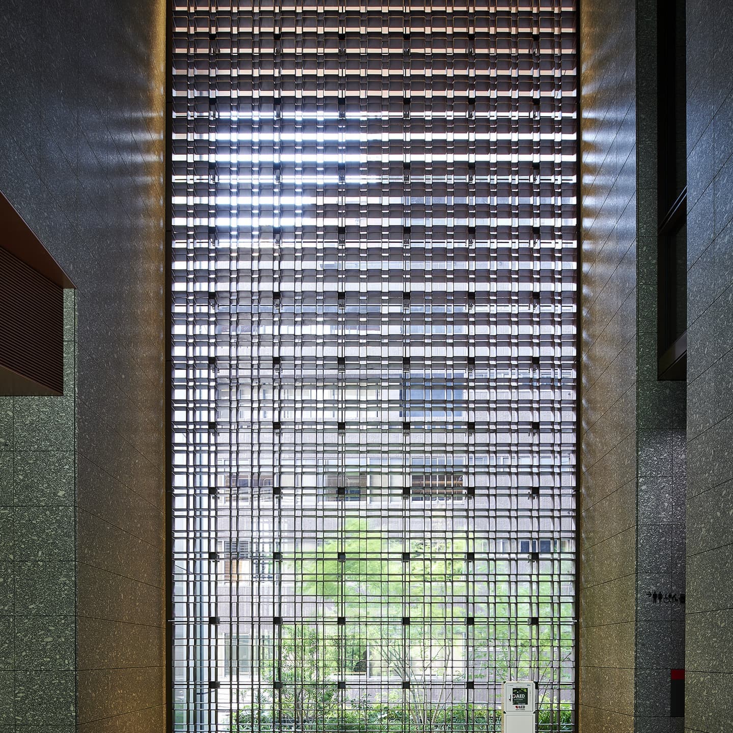 案: alt="建築意図を際立たせる内観撮影。光の透過と格子のディテールを緻密に捉え、空間の静謐さを表現したエントランスホールのビジュアル。