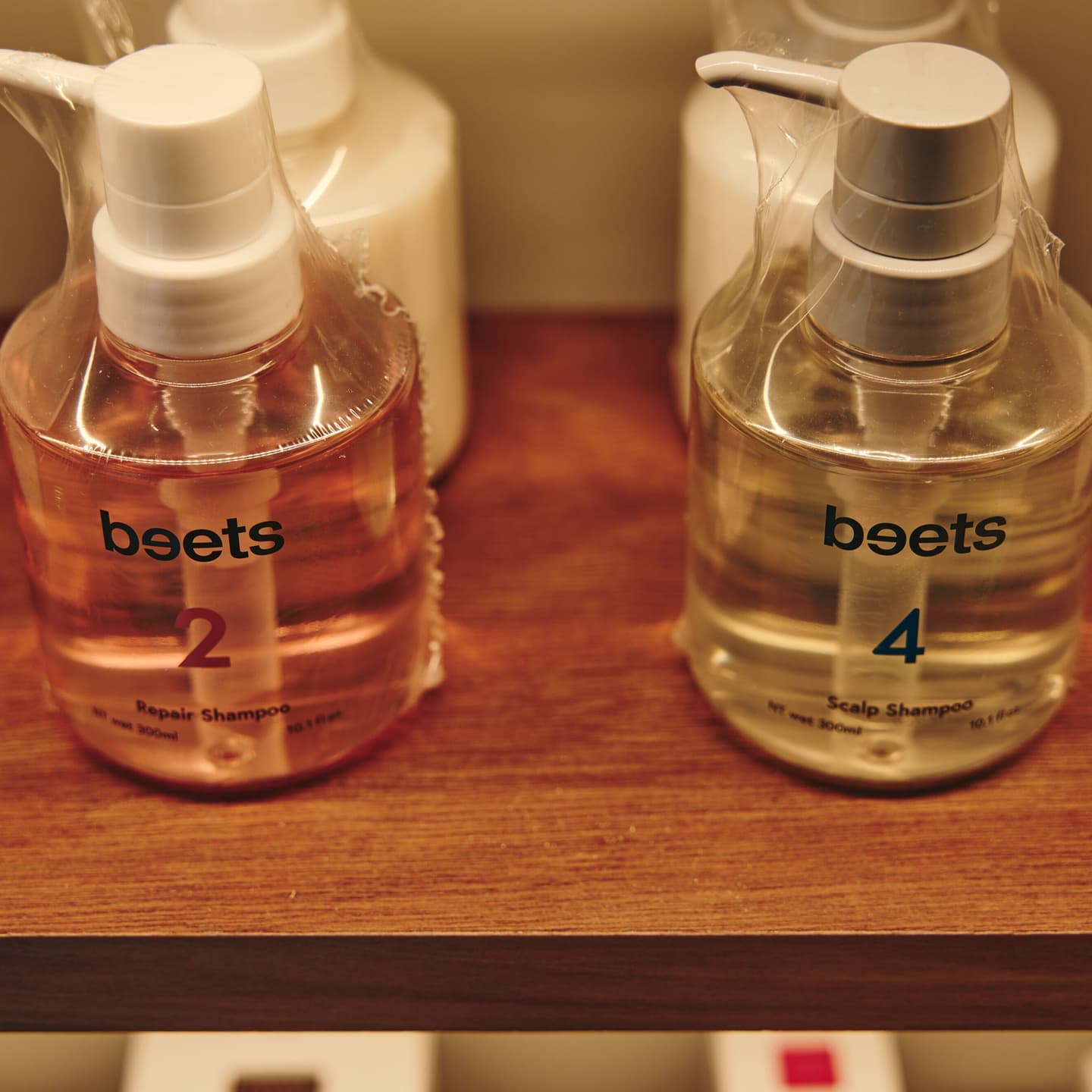 サロン専売品シャンプーのプロダクト撮影。店舗の棚に並ぶ商品の質感を、ブランドのトーンに合わせた柔らかな光で捉えたディテールカット。